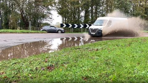 A van driving through a road covered in water