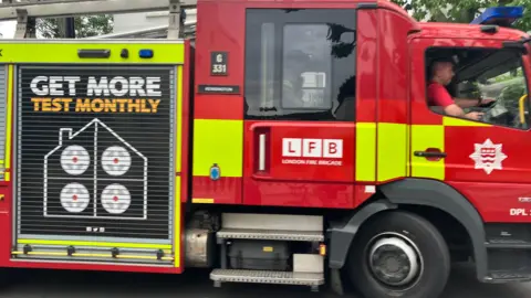 A stock photo showing a red and yellow London Fire Brigade vehicle