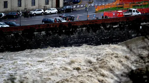 EPA-EFE/REX/Shutterstock The swollen Arno river hits against a black wall beneath a road in Florence.