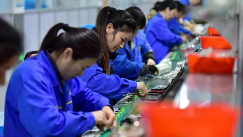 Costfoto / NurPhoto via Getty Images Women workers on a production line in a factory in Fuyang, China adjust circuit breakers while wearing blue overalls, pictured on 4 March.