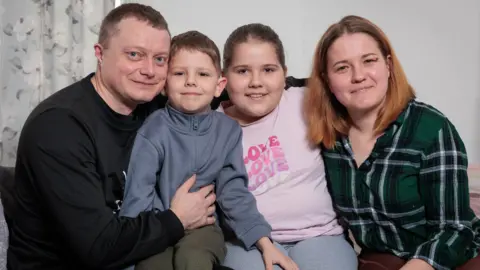 Andy Jones/BBC Ivan Vitsin (left) and Olesia Aladco (right) smiling with their children