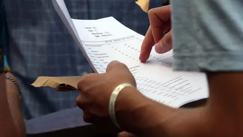 A stock image of a person holding a page that has faint results on it. 