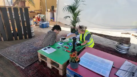 two people being taught how to make solar panels 