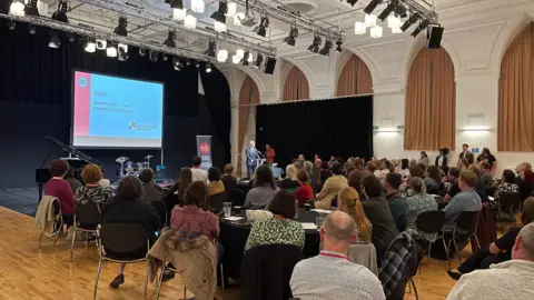 Thomas MacDougall/BBC People gather in a hall to watch a power point display at the launch of the music hub in Barnsley