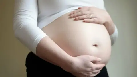 A close-up of a pregnant woman's bump.