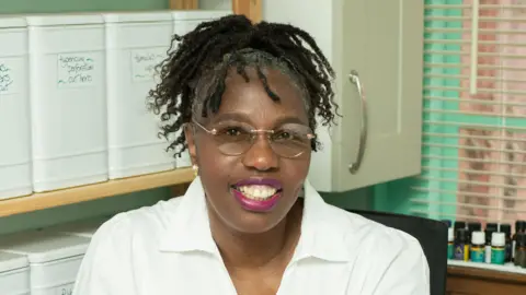 Alice is wearing a white shirt with glasses with no frames. 