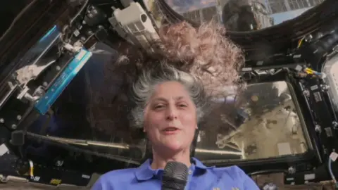 NASA astronaut smiles out of the International Space Station.