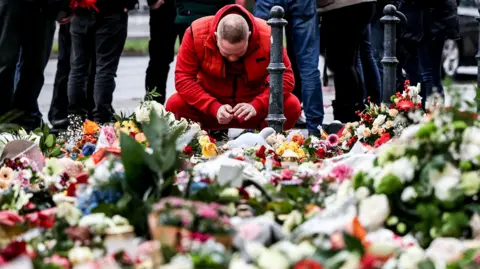 EPA A man mourns at the mourning site in front of St. John's Church following a vehicle-ramming attack on the Christmas market in Magdeburg, Germany,  22 December 2024