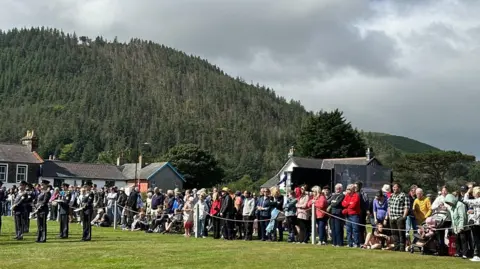 Crowds look on at the guard of honour and band lined up on the fairfield.