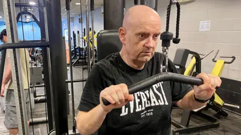 Two images of the same man. The left image is a close up of his face in a hospital bed. He is much heavier and unshaved. Right, he is much slimmer, wearing a black sports t-shirt and pulling on a weight lifting machine.