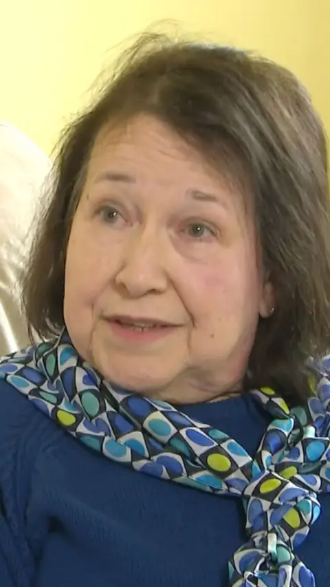 A woman with short brown hair in a blue top.