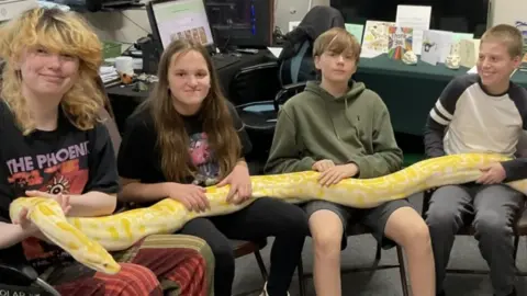 Young people at The Reptile Academy learning about group work and the buddy system when it comes to handling larger animals like Monte the Burmese python.