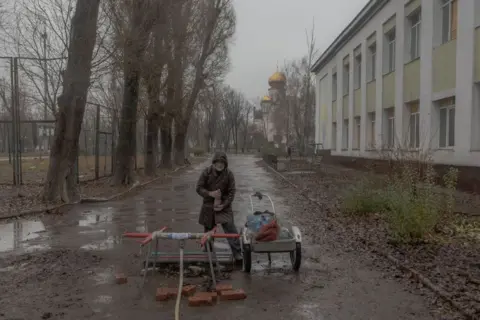 Roman Pilipey/AFP A local resident fills bottles with water in the Ukrainian city Pokrovsk, in the Donetsk region