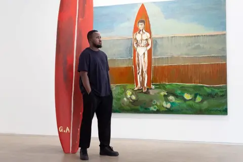 JOEL SAGET / AFP / GETTY IMAGES Gideon Appah stands next to his works at 'Gallery 1957' in Paris.