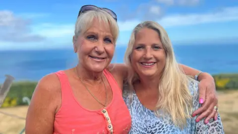 Sadie Wilkins and Victoria Oliver - On the left is Sadie, she has wispy white hair and sunglasses on her head. Sadie is tanned and is wearing a strappy pink blouse. On the right is Victoria, she has long blonde hair and is wearing a blue-tone leopard print blouse.