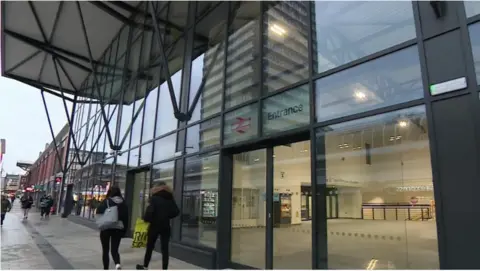 BBC The front of Sunderland station which shows a long concourse of windows and glass and a number of people walking by.