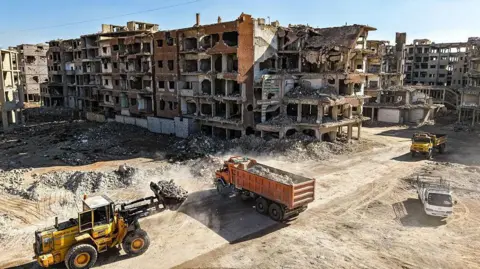 AFP via Getty Images Trucks removing debris from a street in Syria