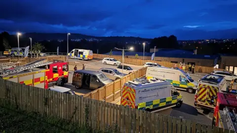 A large group of emergency service vehicles pictured at night on a street
