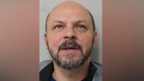 Northumbria Police Mugshot of Nederi. He is bald with a round head and short black and grey beard