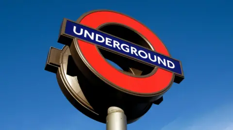 London Underground sign in London, blue sky seen behind. 