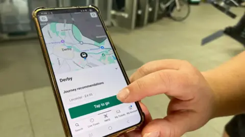 A picture of the PAYG app open on the concourse of a train station - showing the map and GPS identifying the user in Derby