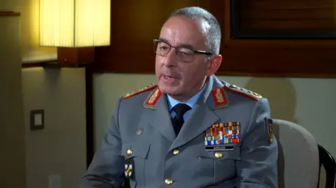 Germany's Chief of Defence Staff, General Carsten Breuer, sits in military uniform during a BBC interview. He has close-cropped hair and glasses.