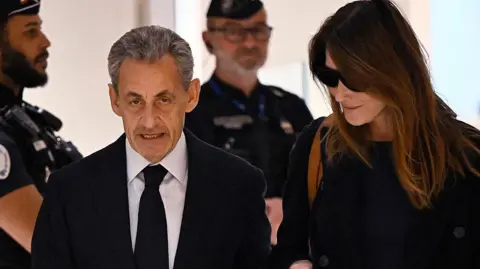 JULIEN DE ROSA/AFP Former French president Nicolas Sarkozy with his wife Carla Bruni arrives for the verdict in his trial for illegal campaign financing from Libya for his successful 2007 presidential bid