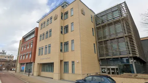 Huntingdon law Courts. A large modern brick-built building. There are two adjoining buildings, both four storeys high. One is dark brick, the other block has sand-coloured bricks.