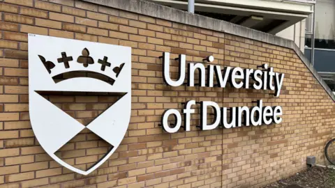 A sign reading University of Dundee attached to a stone building