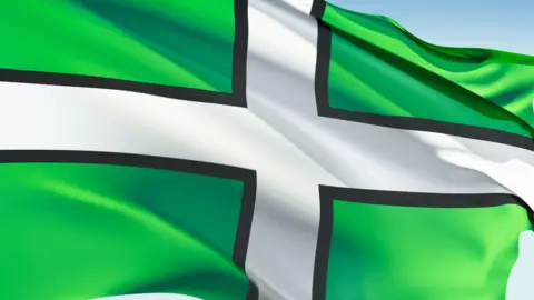 The flag of Devon which is green with a white cross, bordered by black