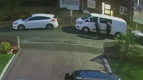 Neighbour CCTV CCTV showing the van parked on a road on the right of the photo before it was taken. The street goes from left to right in the middle of the image.