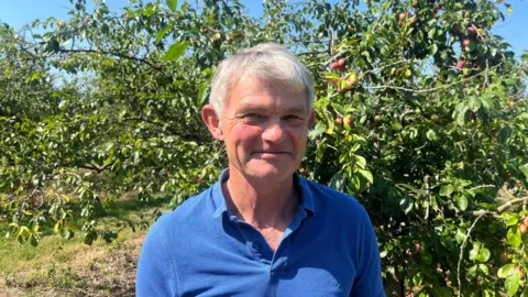 Tom Maynard standing in an orchard