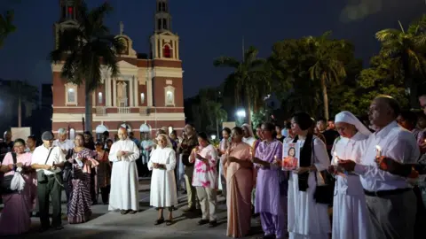 People hold candles as they attend a vigil for the victims of an Air India plane crash