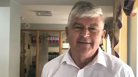 Camelot Care Graham Oakes in a white shirt