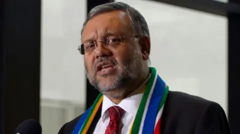 EPA Ebrahim Rasool, wearing a suit and a scarf in South African colours, speaking in 2013.