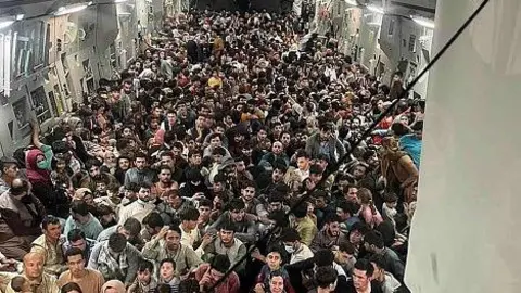 US Air Mobility Command The inside of a military cargo plane with hundreds of people crammed inside