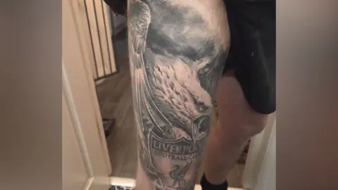 Image of Martin Smith's leg tattoo of an eagle and Liverpool United Football club logo.