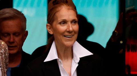 Celine Dion smiles as she walks out of the hotel
