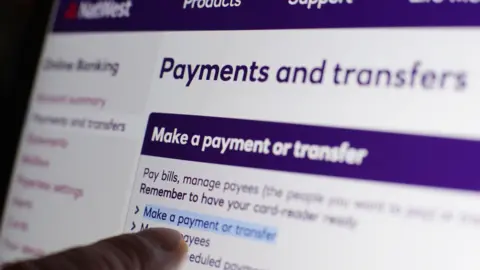 PA A finger pointing at a banking screen - towards a highlighted area that says "Make a payment or transfer"