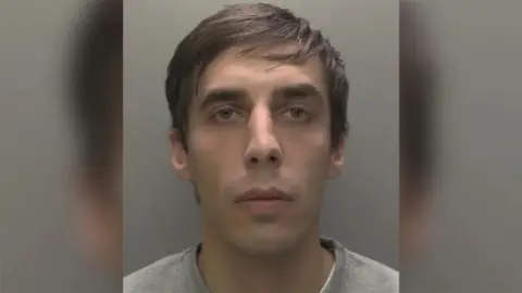 Humberside Police custody photo of Mark Vaskouski who is clean shaven with black hair and wearing a gray shirt