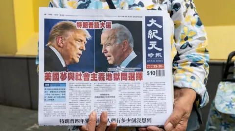 Getty Images A newspaper vendor in Hong Kong, China, distributes a daily featuring coverage of the US presidential debate