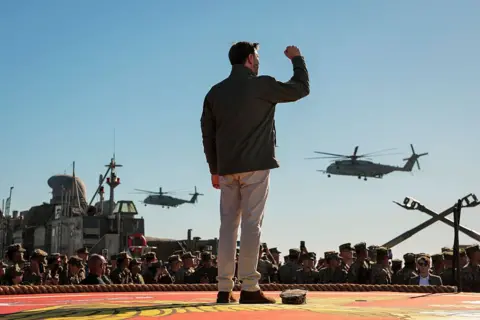 Getty Images JD Vance raises his fist as a military helicopter flies by