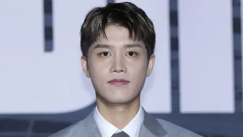 Taeil, former member of the K-pop band NCT, dressed in a gray suit, white shirt and gray tie, poses for the camera at a press conference in Seoul, in September 2022