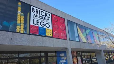 Brickz Museum The outside of Brickz Museum in Milton Keynes. It is a grey concrete building, with a large "Brickz Museum" sign and large Lego structures on show behind the windows.