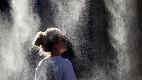 A woman cools off under a mist sprayer in Bordeaux, France.