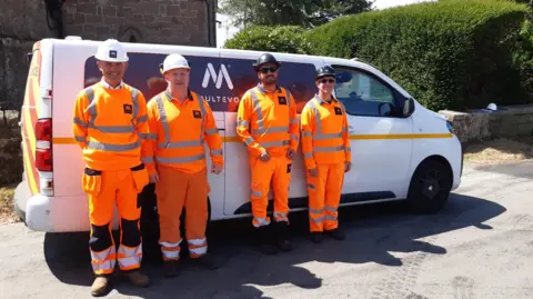 LDRS Four men wearing orange hi-vis outfits and white helmets are standing in front of a small white van with the word "multevo" on the front