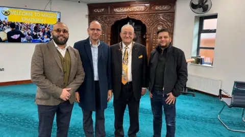 Masjid Khadijah and Islamic Centre Marco Cereste, wearing his chain of office, standing alongside other people at the mosque.