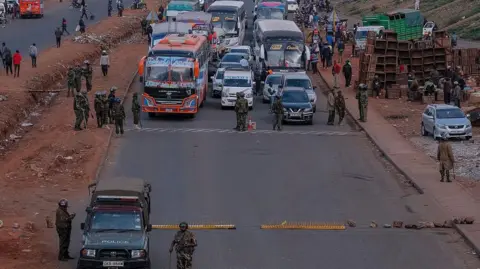 AFP via Getty Images Police officers man a roadblock with buses and and other vehicles stopped from entering Nairobi central business 