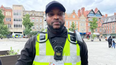 Ibrahim Jollah is wearing high-visibility uniform and recording devices. 