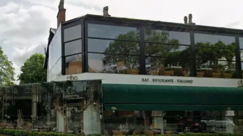 The exterior of Cibo restaurant. There are tables and chairs outside the large restaurant, which is a glass-fronted two-storey building.